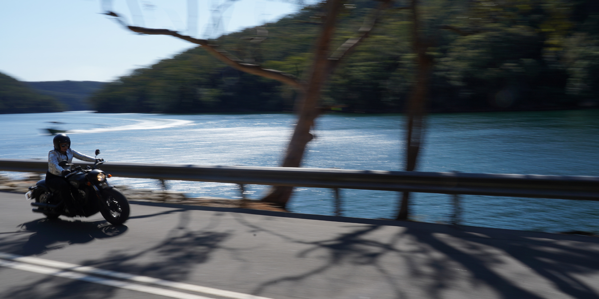 Motorcyclist wearing a helmet with a Hightail on it looking at the coast