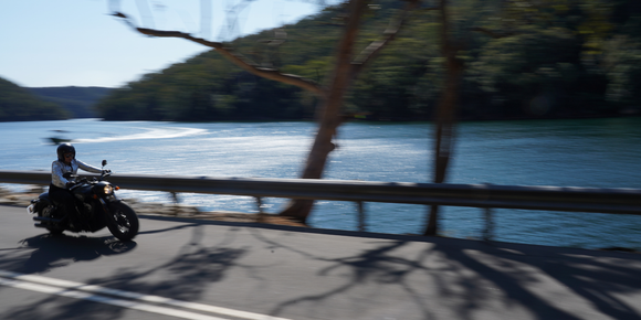 Motorcyclist wearing a helmet with a Hightail on it looking at the coast